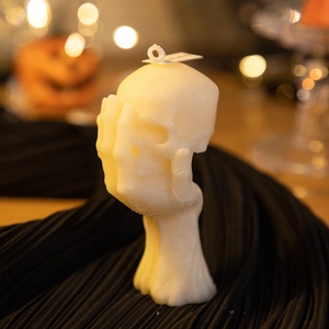 Artistic skull candle held by a skeletal hand with warm bokeh lighting detail