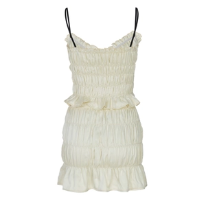 Detailed close-up of smocked fabric and ruffled hem on a beige chiffon strap dress