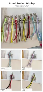 Close-up of heart-shaped metal pendant with colorful woven tassels and lobster clasp
