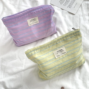 Striped canvas cosmetic bags in lavender and yellow displayed on white fabric