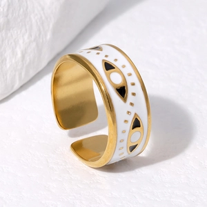 Detailed close-up of golden evil eye ring with black and white enamel drip on marble