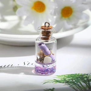 Detailed macro view of a miniature glass drift bottle charm with purple crystals and shells
