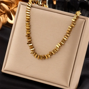 Golden beaded woven necklace with 3D triangle pendants on a beige jewelry box