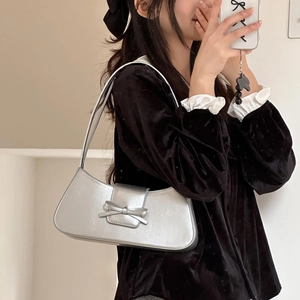 Silver metallic leather baguette shoulder bag with bow detail worn by a model