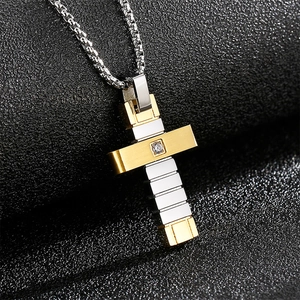 Gros plan d'un pendentif croix bicolore or et argent avec cristal sur fond noir texturé