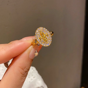 Close-up of golden vintage ring with fleur-de-lis pattern and dangling star charm