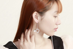 Detail of silver clover heart earrings with sparkling rhinestones and white pearls on model