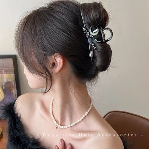 Elegant silver metal hair claw with blue flowers and pearls shown on a bun
