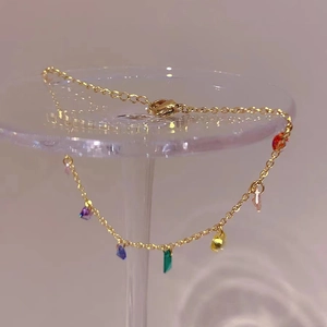 Detail of a thin gold titanium necklace with vibrant multi-colored zircon pendants