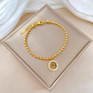Close-up of golden beaded bracelet with dual-heart pendant and S-Steel engraving detail