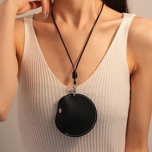 Detail of round black PU leather necklace pouch for Airtag with woven lanyard and snap closure