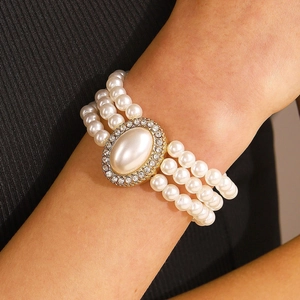 Gros plan d'un bracelet de perles à trois rangs avec fermoir ovale doré en strass