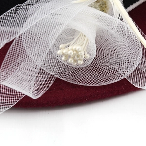 Dettaglio cappello in lana con fiore a rete, perle e piume bordeaux e bianco