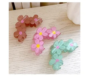 Detail of three flower hair claws in candy colors on a light wood background
