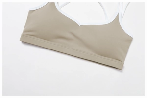Close-up of contrast binding on a V-neck khaki sports bra with elastic white straps