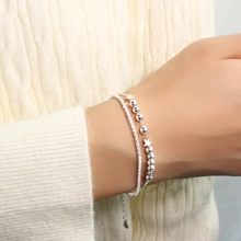 Silver double-layer star bracelet worn on wrist over a soft beige knit sweater sleeve