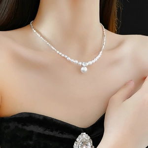Detail view of silver chain necklace with zircon and faux pearls worn on collarbone