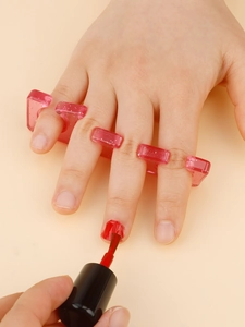 Detailed view of pink silicone toe separator being used for applying red nail polish