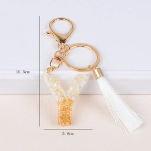 Detail view of resin letter Y keychain with gold foil, white stones and long silk tassel