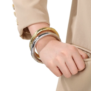 Polished stainless steel chunky bangles in gold and silver finish on a model's wrist