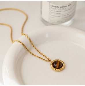 Macro detail of retro tiger eye pendant on a golden twisted chain necklace