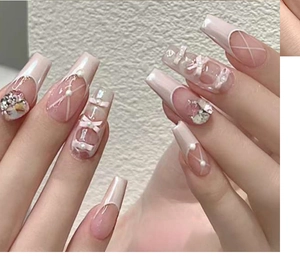 Close-up of pink french ballerina press-on nails with 3D bows and pearl accents