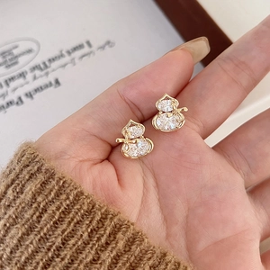 Elegant gold plated gourd stud earrings with zircons shown on model hand