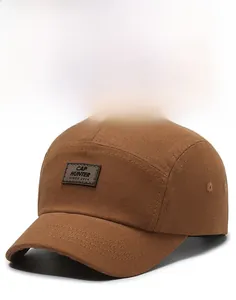 Dettaglio del cappellino 5-panel marrone vintage con toppa in pelle e tesa rigida
