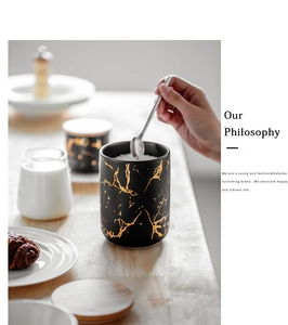 Detail of black ceramic jar with gold marble texture and light wood lid in kitchen setting