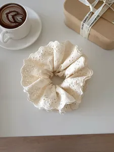 Detail of premium off-white lace scrunchie with intricate hollow embroidery texture