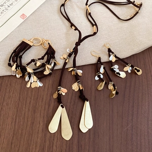 Detail view of brown cord jewelry set with gold and silver metallic teardrop pendants