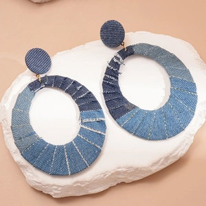 Chic hollow oval denim fabric hoop earrings with silver pins on a white stone background