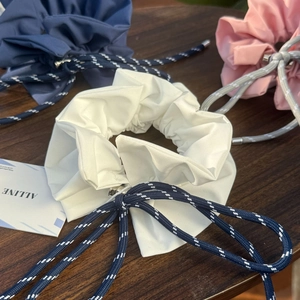 Close-up of fabric hair scrunchies with woven drawstrings and metal tips on wood