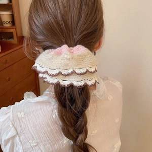 Close-up of knit lace scrunchie with tri-color design styled on a low ponytail