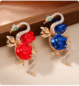 Detailed view of snake and rose enamel brooches with crystals on beige fabric