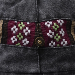 Macro shot of washed cotton fabric with ethnic embroidery and bronze snap button detail