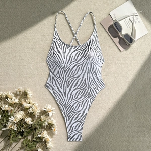Detailed view of backless zebra print swimsuit with cross straps on a textured rug