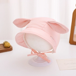 Close-up of pink baby hat with rabbit ears and corduroy details on a white model