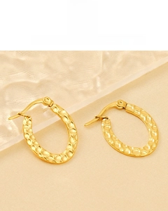 Detail of 18K gold plated oval earrings with hammer-textured finish on silk background