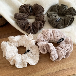 Detail of knitted ruffle scrunchies in olive, cream, and pink with fashion label texture
