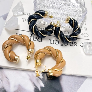 Detail of twisted leather C-shape earrings with gold wire wrap in black and brown