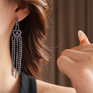 Détail de boucles d'oreilles à longs pompons argentés avec cristaux violets portées
