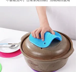 Blue silicone honeycomb mat used to safely lift a hot ceramic pot lid in the kitchen