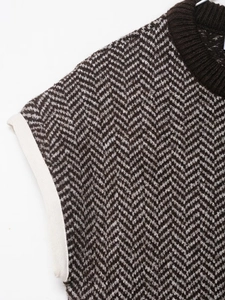Close-up of herringbone knit vest featuring brown ribbed collar and detailed texture