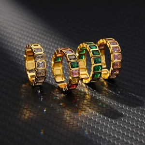 Macro shot of geometric gold rings featuring rectangular colored zircon stones on black carbon