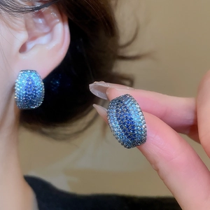 Macro shot of blue gradient micro-pave C-shape earrings with zircon stones for women