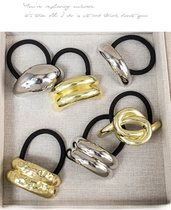 Close-up of assorted gold and silver metal charms on elastic hair ties in a tray