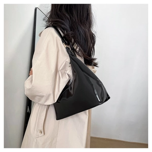 Glossy black patent leather baguette bag shown as a shoulder hobo bag on a model