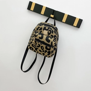 Detail of leopard print mini backpack with golden zippers hanging on a wall hook