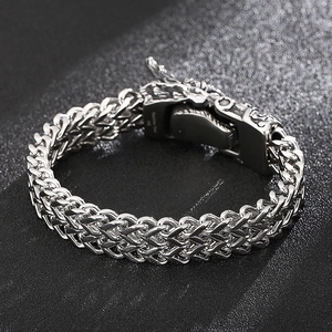 Macro shot of stainless steel dragon head clasp and braided curb chain bracelet
